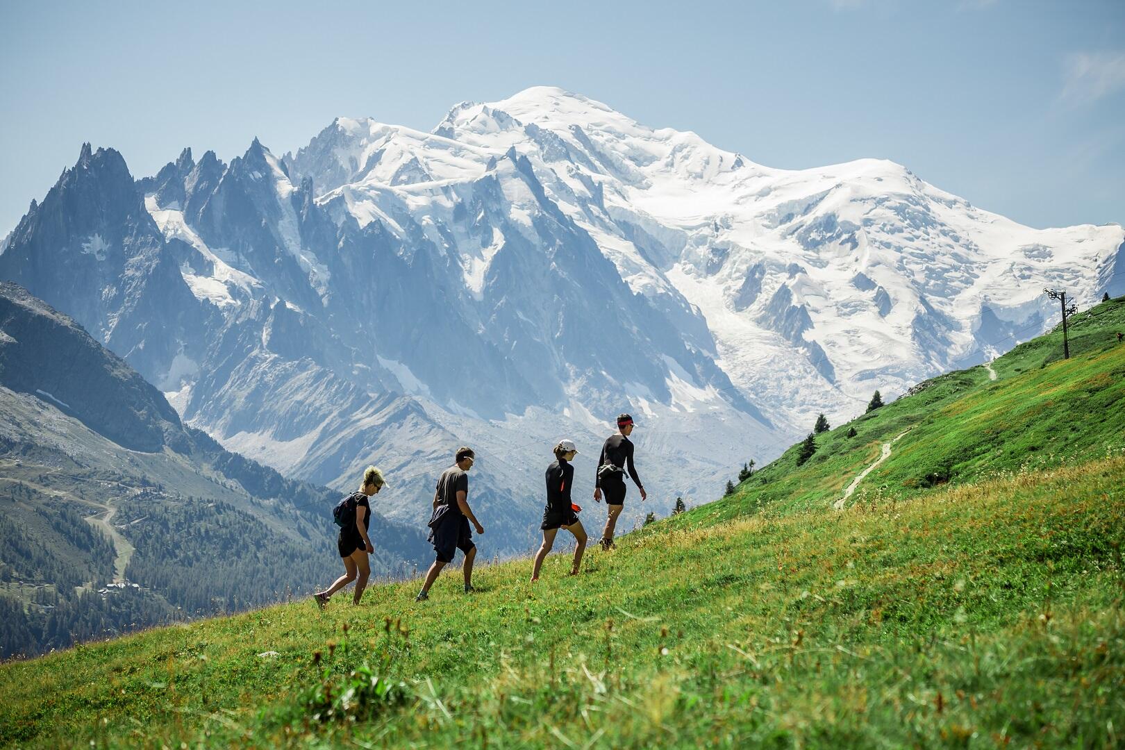 quatre randonneurs entrain de marcher sur un sentier de randonnée à la montagne. Cela met en avant la journée nationale de la randonnée